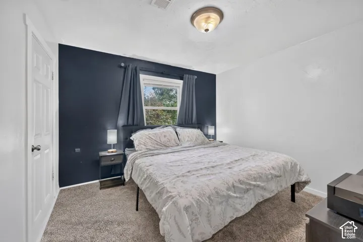 The primary bedroom has carpet, a navy accent wall and a window facing the trees. It sits on the side of the house, right beside the bath.