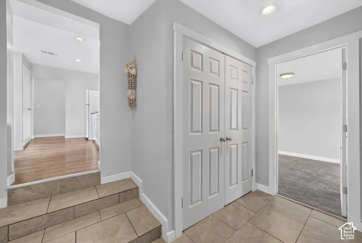 The tiled back entry has the laundry behind the double doors, with a few steps up to the kitchen. A carpeted bedroom opens off it, through the doorway on the right.