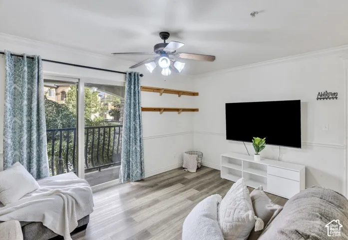 LVP flooring, ceiling fan with integrated lighting, wall-mounted shelving, chair rail molding, and sliding glass doors with balcony access