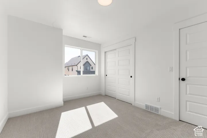 Neutral-toned wall-to-wall carpeting, white five-panel interior doors, sliding closet doors, and a double-pane window