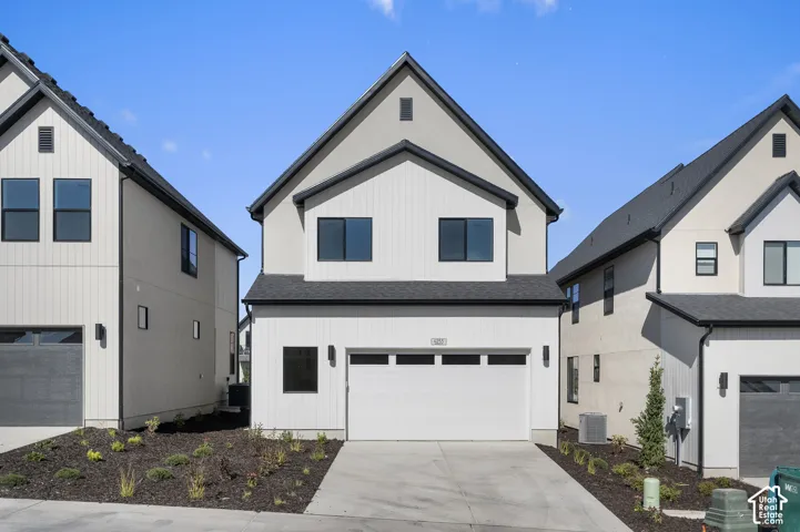 Two-story exterior featuring vertical board-and-batten siding, a gabled roofline, multi-pane garage door, and dark metal-finish window frames