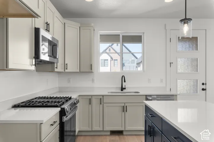 Kitchen featuring shaker-style cabinetry, quartz countertops, a stainless steel gas range with built-in microwave, a dark-toned center island, and a glass-paneled exterior door