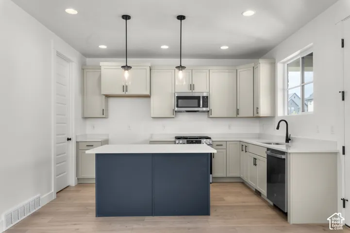 Kitchen featuring light-toned cabinetry, a contrasting center island, light-toned countertops, recessed lighting, and dual pendant lights