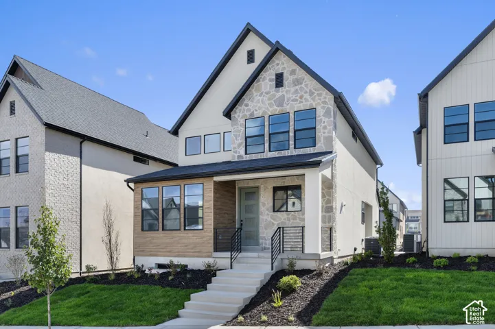Contemporary exterior featuring a stone masonry facade, horizontal wood-finish siding accents, multi-pane windows, and a concrete staircase leading to a covered entrance with black metal railings