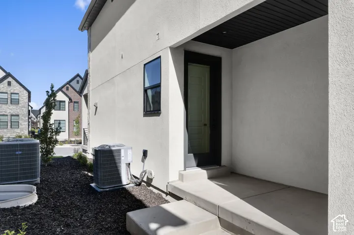 Stucco exterior featuring a concrete entry stoop, recessed ceiling, glass-panel door, and dark-finished trim