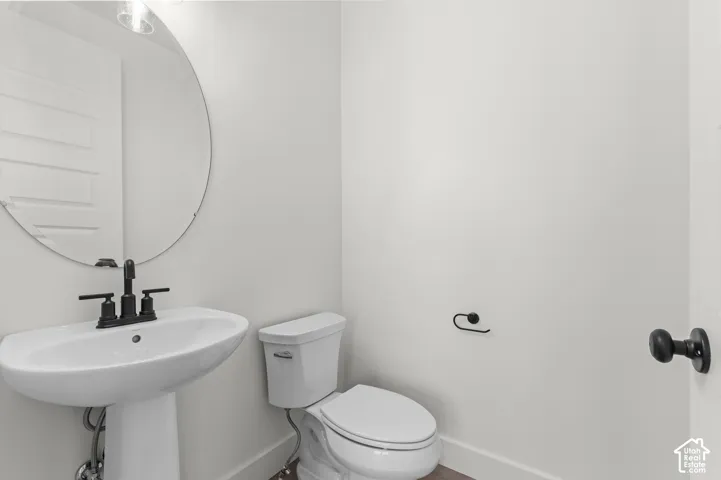 Pedestal sink featuring a matte black widespread faucet, circular wall-mounted mirror, and matching matte black hardware