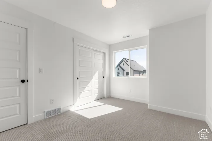 Neutral wall color, wall-to-wall carpeting, four-panel interior doors, and a single-hung window with casing