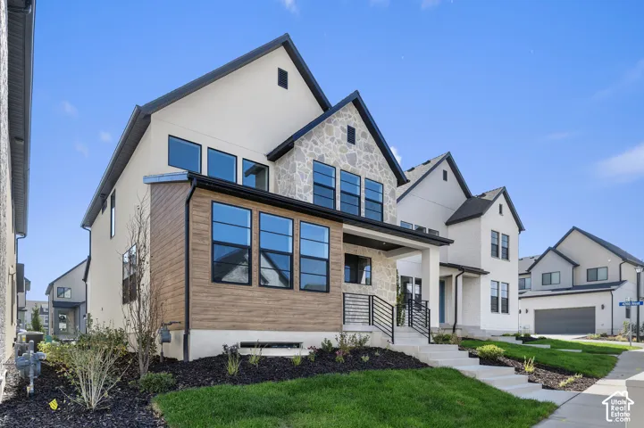 Multi-level exterior featuring a combination of stone masonry, wood-finish siding, and smooth stucco finish, accented by black metal railings and concrete stairs