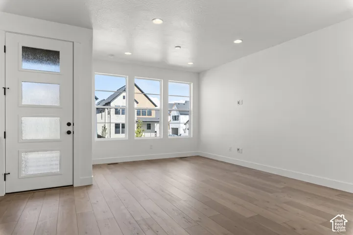 Entry area featuring wood-finish flooring, recessed lighting, and a door with four frosted glass panels, complemented by three large windows