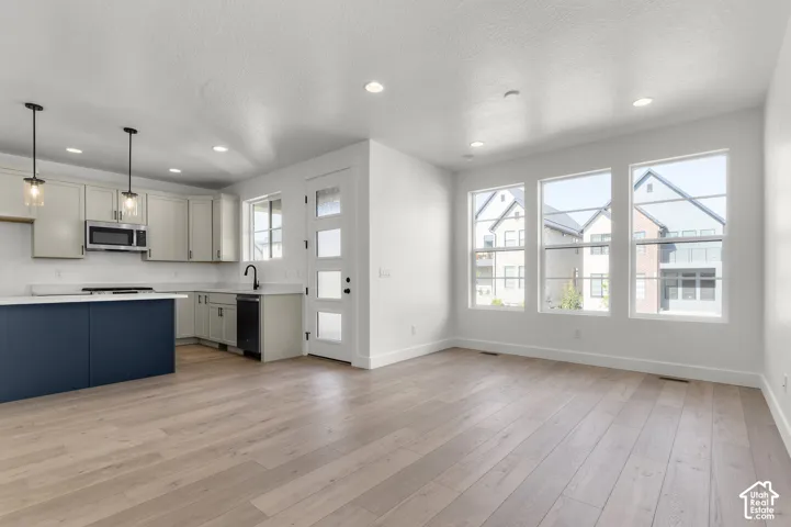Kitchen featuring light-colored cabinetry, a contrasting center island, quartz countertops, wood-finish flooring, and recessed lighting