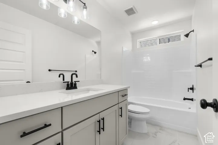 Bathroom featuring a light-toned vanity with a quartz countertop, matte black fixtures, integrated lighting, and a tub-shower combination with white subway-style tile surround