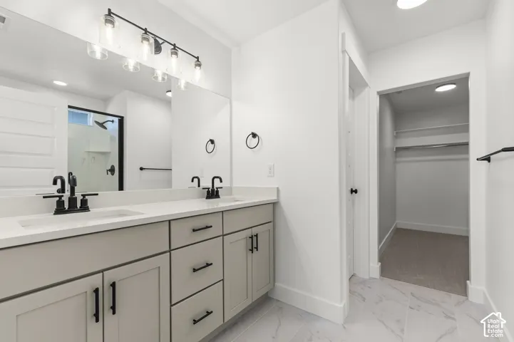Dual-sink vanity with light-gray cabinetry, stone-finish countertops, matte black fixtures, and large-format tile flooring