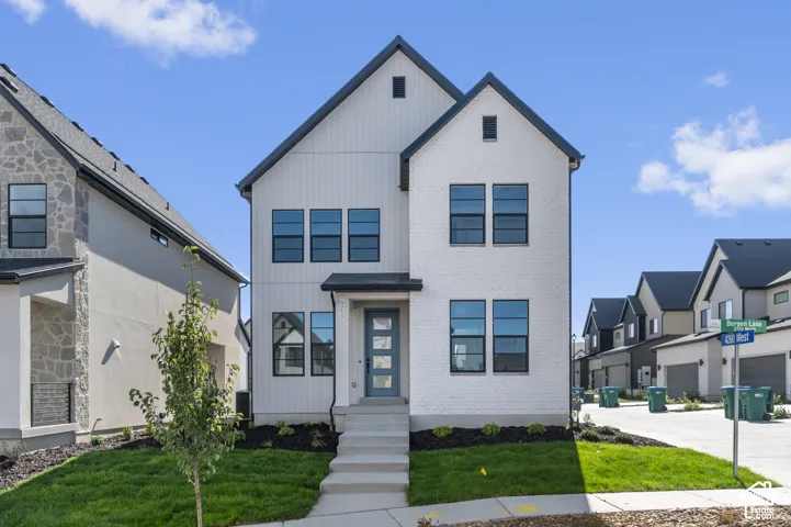 Multi-story exterior featuring white brick and vertical siding, a covered entryway, and dark-framed windows