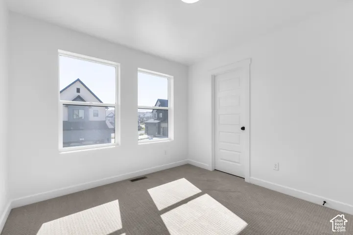 Neutral-toned wall-to-wall carpeting, dual picture windows, and five-panel interior door with matte black hardware