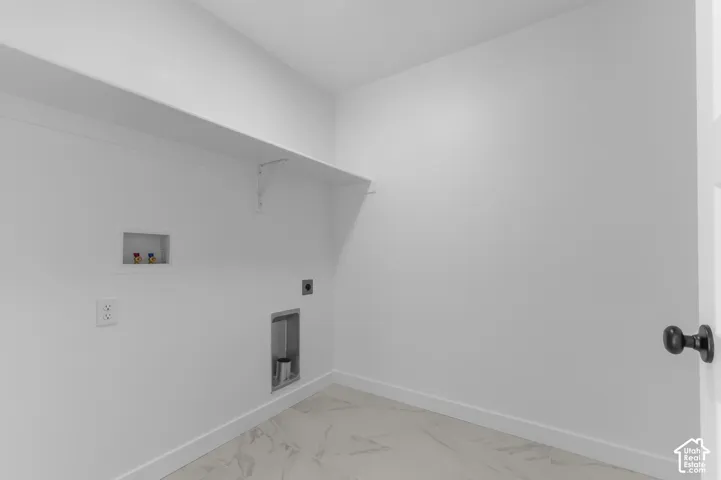 Utility space featuring stone-style tile flooring, built-in shelving, and recessed laundry hookups
