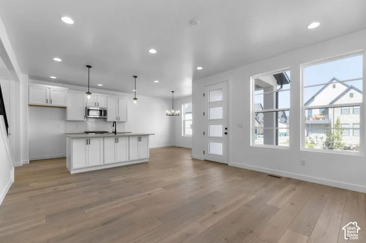 Kitchen featuring white cabinetry, an island with stone-finish countertops, wood-finish flooring, recessed lighting, and a multi-pane glass entry door