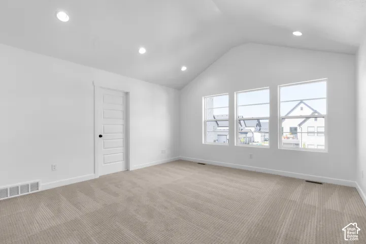 Vaulted ceiling featuring recessed lighting, carpeted flooring, and a five-panel interior door