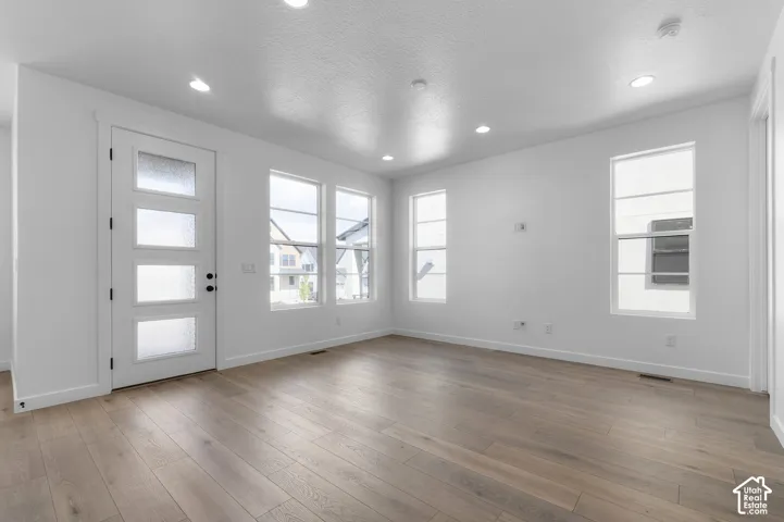 Interior space featuring wood-finish flooring, recessed lighting, and a multi-panel door with frosted glass inserts, complemented by numerous large windows with mullions