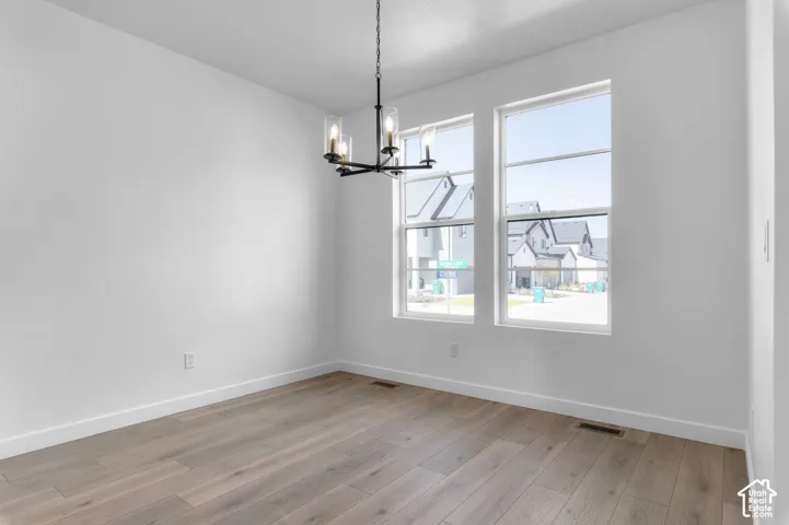 Room with wood-finish flooring, dual windows with multi-pane glass, and a matte black geometric chandelier with clear glass cylindrical shades