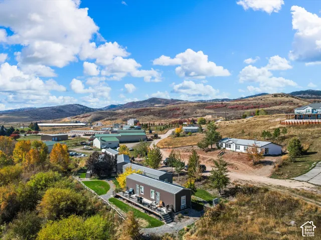 Aerial perspective of the property featuring a metal-roofed structure, a deck, and surrounding mountainous terrain