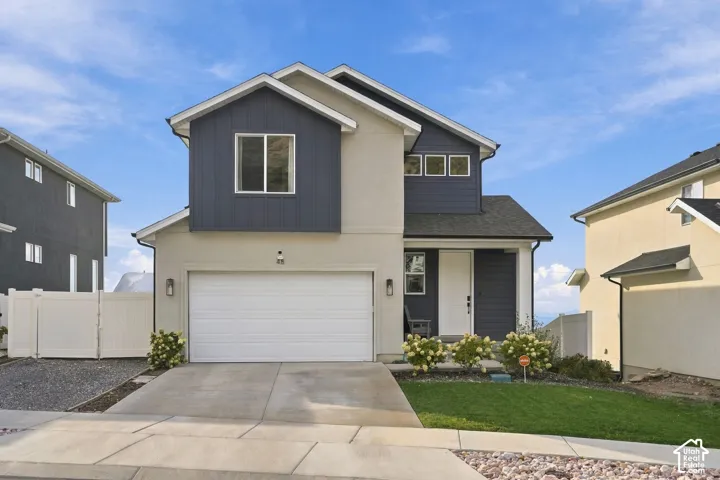 Two-story exterior featuring a mix of vertical board-and-batten siding and stucco, a two-car garage, concrete driveway, and professional landscaping