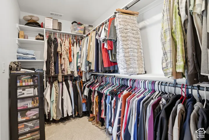 Walk-in closet featuring tiered clothing rods and built-in shelving