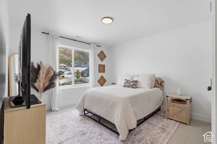 Interior room featuring neutral wall-to-wall carpeting, a large picture window, a flush-mount circular ceiling light, and mountain landscape imagery