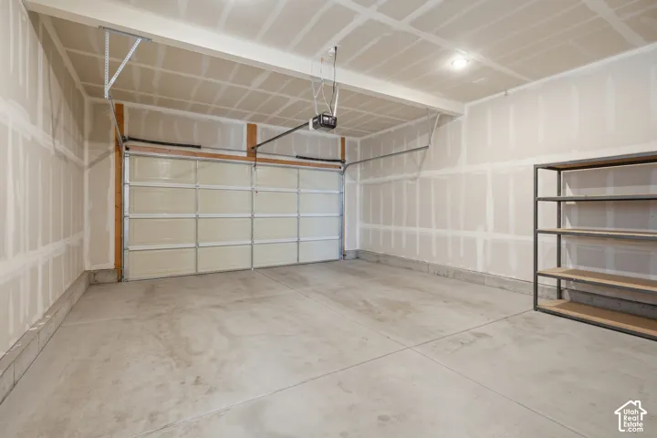Multi-car garage featuring a concrete floor, finished drywall surfaces, and an overhead automatic garage door opener
