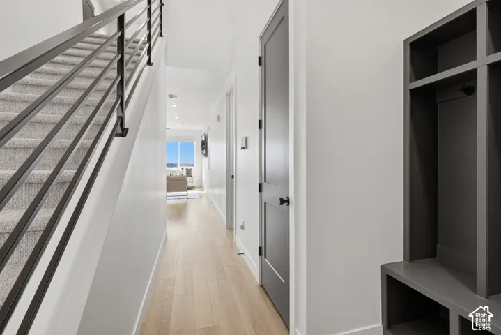 Interior hall featuring wood-finish flooring, staircase with metal horizontal railing, charcoal-finished built-in storage cabinetry, and painted interior doors with matte black hardware