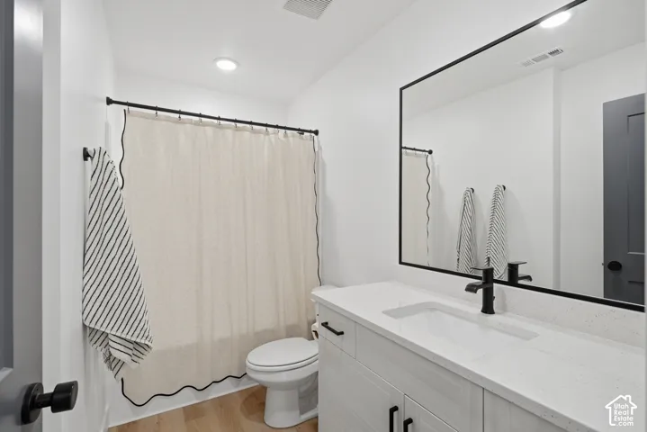Vanity featuring a light-toned wood-finish cabinet, stone-composite countertop with an integrated basin, and a matte black faucet
