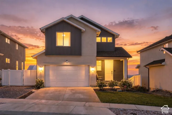 Two-story exterior featuring a mix of stucco and vertical siding, a two-car garage, and a covered entry