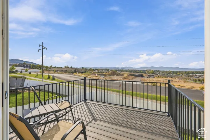 Elevated deck featuring composite decking and a black metal railing, showcasing mountain scenery and an open landscape
