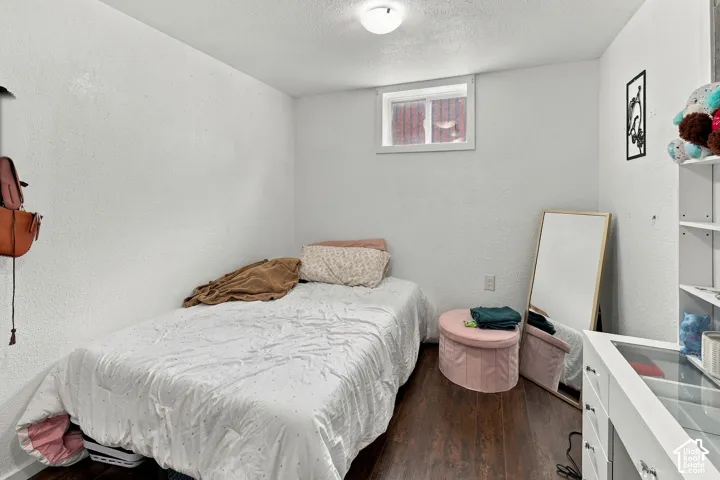 Interior room featuring dark wood-finish flooring, textured walls, a ceiling-mounted light fixture, and an inset slider window