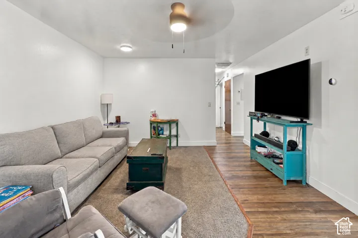 Room featuring wood-finish flooring, wall-to-wall carpeting, and a central ceiling fan with integrated lighting