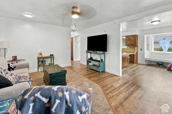Living area featuring wood-finish flooring, recessed ceiling lighting, a central ceiling fan, and a built-in window seat