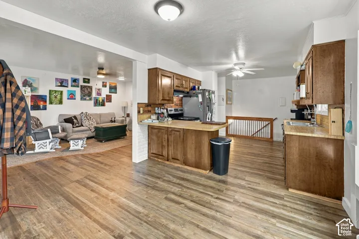 Kitchen featuring stained wood cabinetry, stone-texture laminate countertops, wood-finish flooring, and a white brick support column