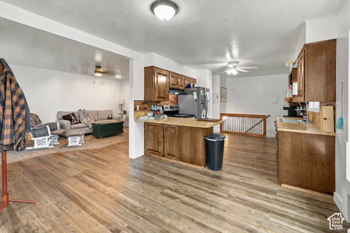 Kitchen featuring wood-finish cabinetry, a peninsula, and wood-finish flooring with a white brick support wall