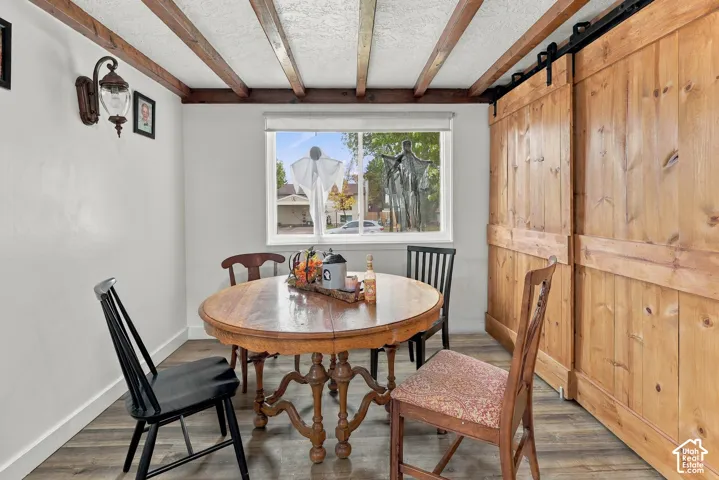 Exposed timber ceiling beams, wood-finish flooring, sliding barn-style doors, and decorative wall-mounted lighting