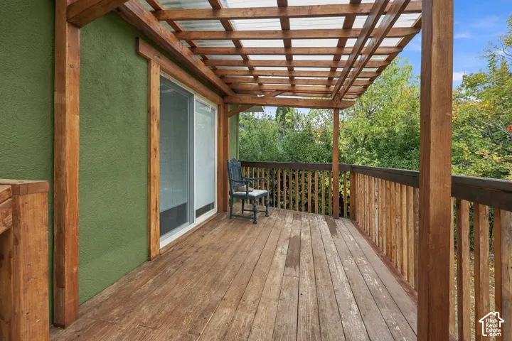 Outdoor deck featuring wood plank flooring, a slatted timber pergola, and vertical wood railing