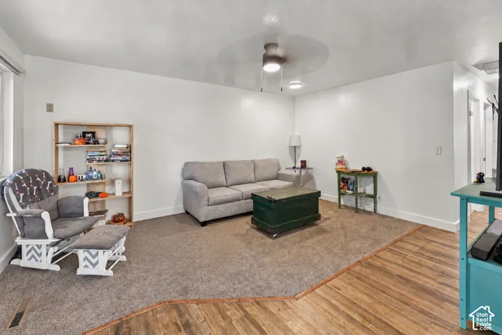 Neutral interior space featuring wood-finish flooring, wall-to-wall carpeting, and a ceiling-mounted light fixture with an integrated fan