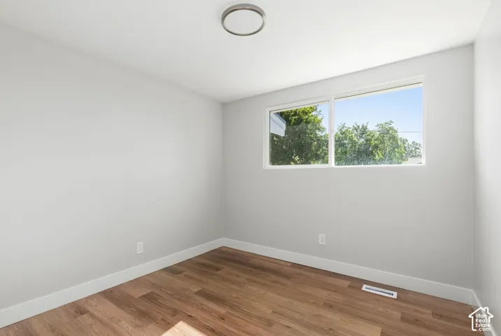 Wood-finish flooring, white trim, flush mount ceiling light, and dual pane windows