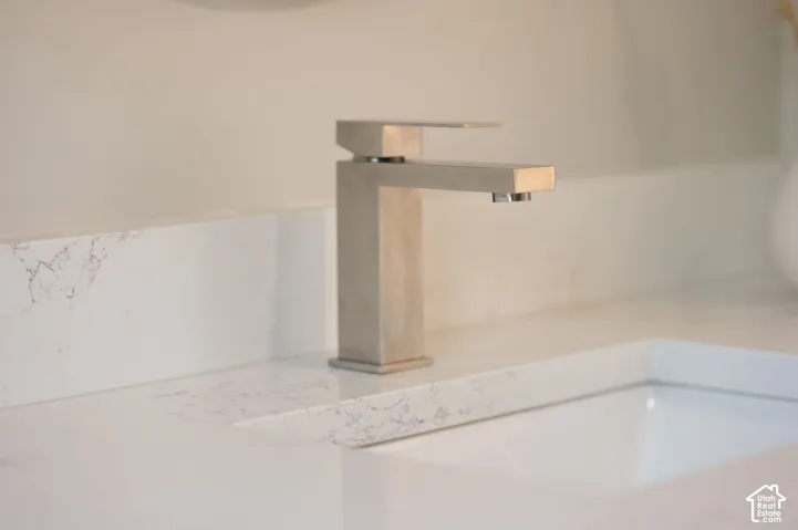 Modern brushed nickel faucet with a square profile set on a white countertop with integrated sink