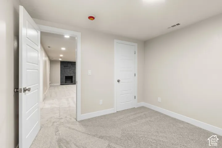 Carpeted room with white trim, leading to a space with a stone fireplace and recessed lighting