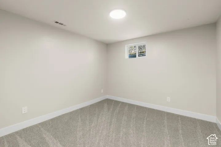 Neutral tone wall finish, window with white trim, recessed ceiling light, and gray patterned carpeting