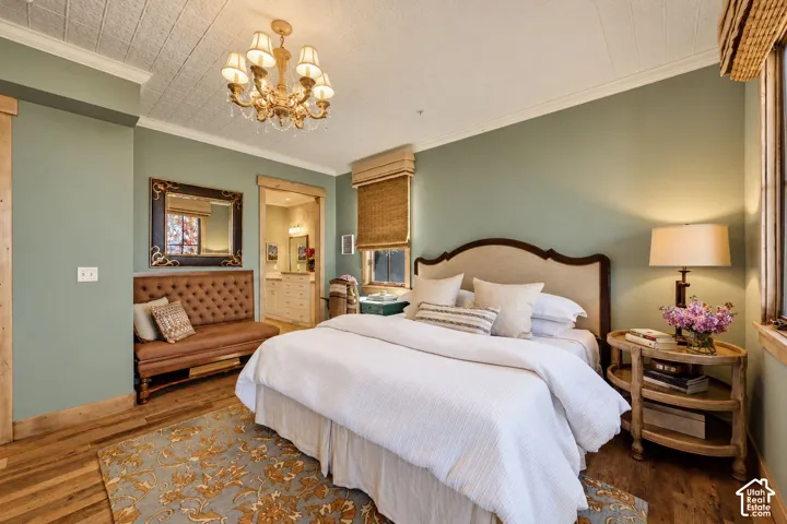 Wood-finish flooring, ornate multi-arm chandelier, decorative coffered ceiling detail, and natural wood door and window casing