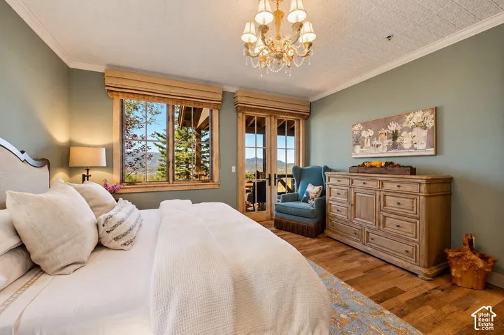 Room featuring wood-finish flooring, a decorative multi-arm chandelier, wood-trim windows, and glass-paneled exterior doors with mountainous scenery