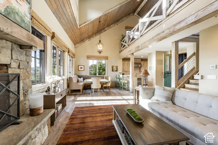 Vaulted wood-plank ceiling, stone-surround fireplace, exposed timber beams, mezzanine level with decorative railing, and wood-finish flooring