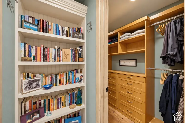 Built-in floor-to-ceiling shelving with beadboard backing, custom wood-finish closet cabinetry, integrated storage drawers, and dual-level hanging rods