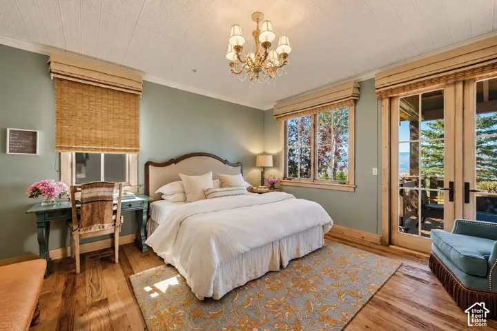 Hardwood flooring, ornate metal chandelier, wood-trimmed multi-pane windows, and glass-paned double doors