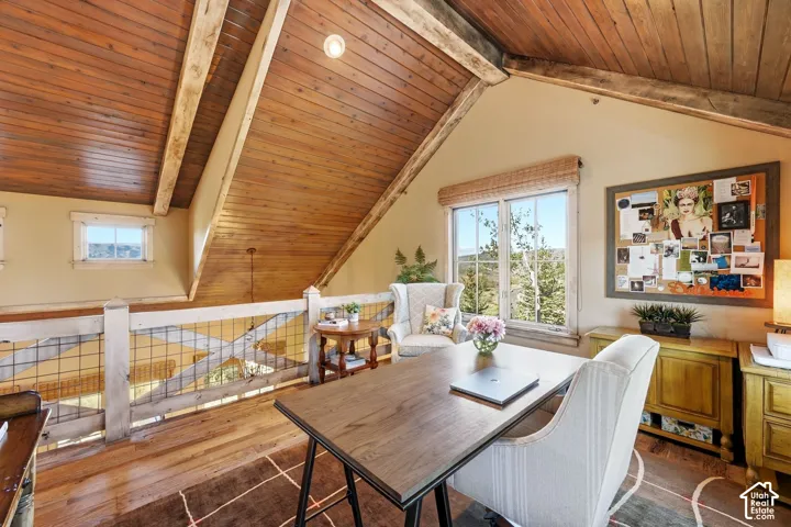 Vaulted ceilings featuring exposed timber beams and tongue-and-groove wood paneling, wood-finish flooring, and a decorative railing with integrated wire mesh